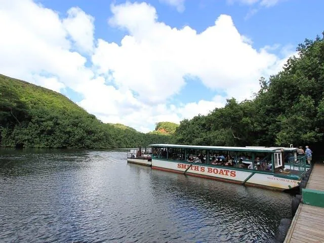 Ein langes Ausflugsboot hat an einem Holzsteg an einem Fluss angelegt.