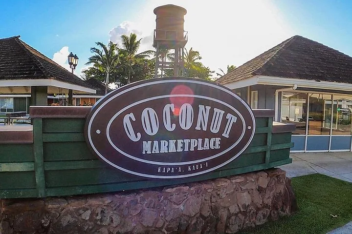 A sign for Coconut Marketplace in Kapaa, Kauai with wooden buildings.